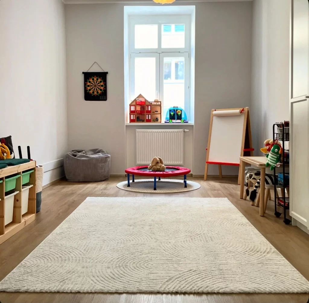 Kindertherapieraum mit Spielteppich, Trampolin und Dartscheibe